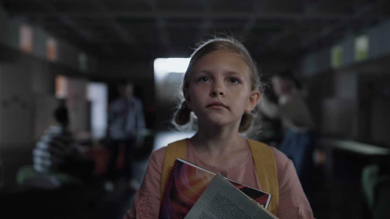 Ritratto di una bambina che cammina in un corridoio vivace con in mano dei libri. La bambina percorre il corridoio.