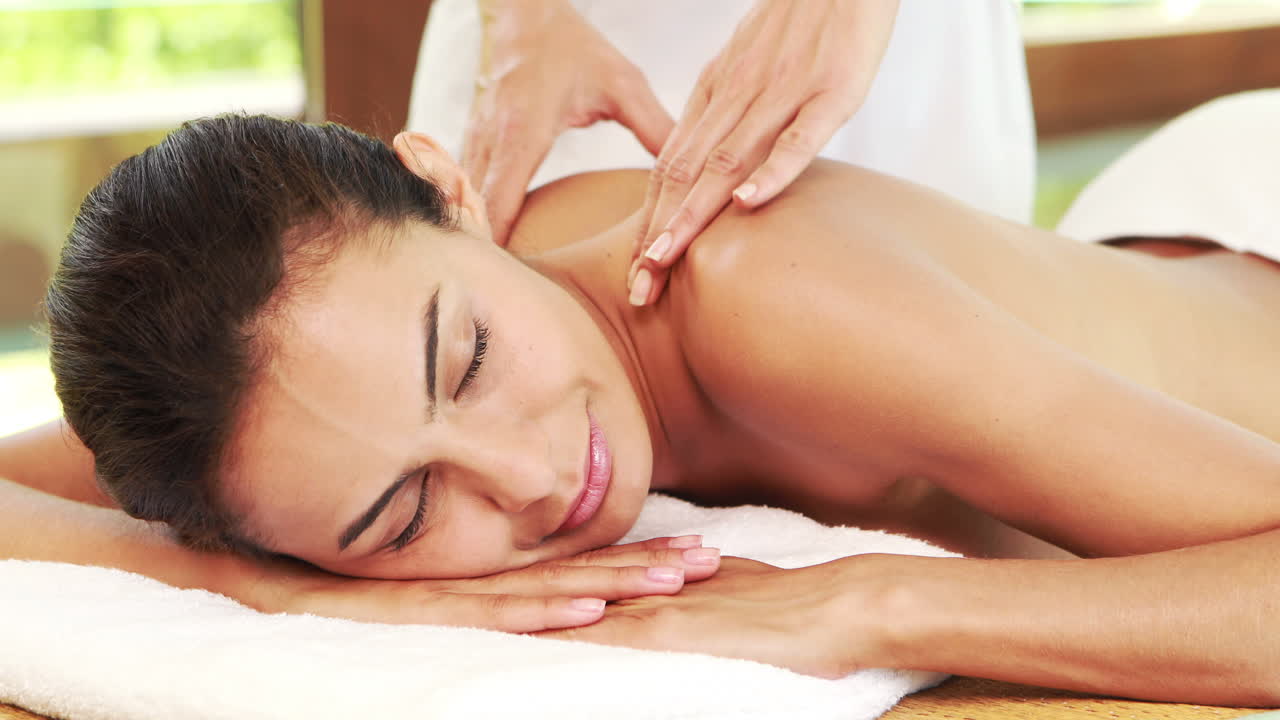 젊은 여성이 뜨거운 돌 마사지를 받고 있습니다.