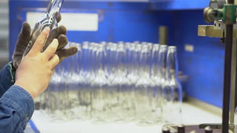 expert inspecting a glass bottle in slow motion at a bottle factory