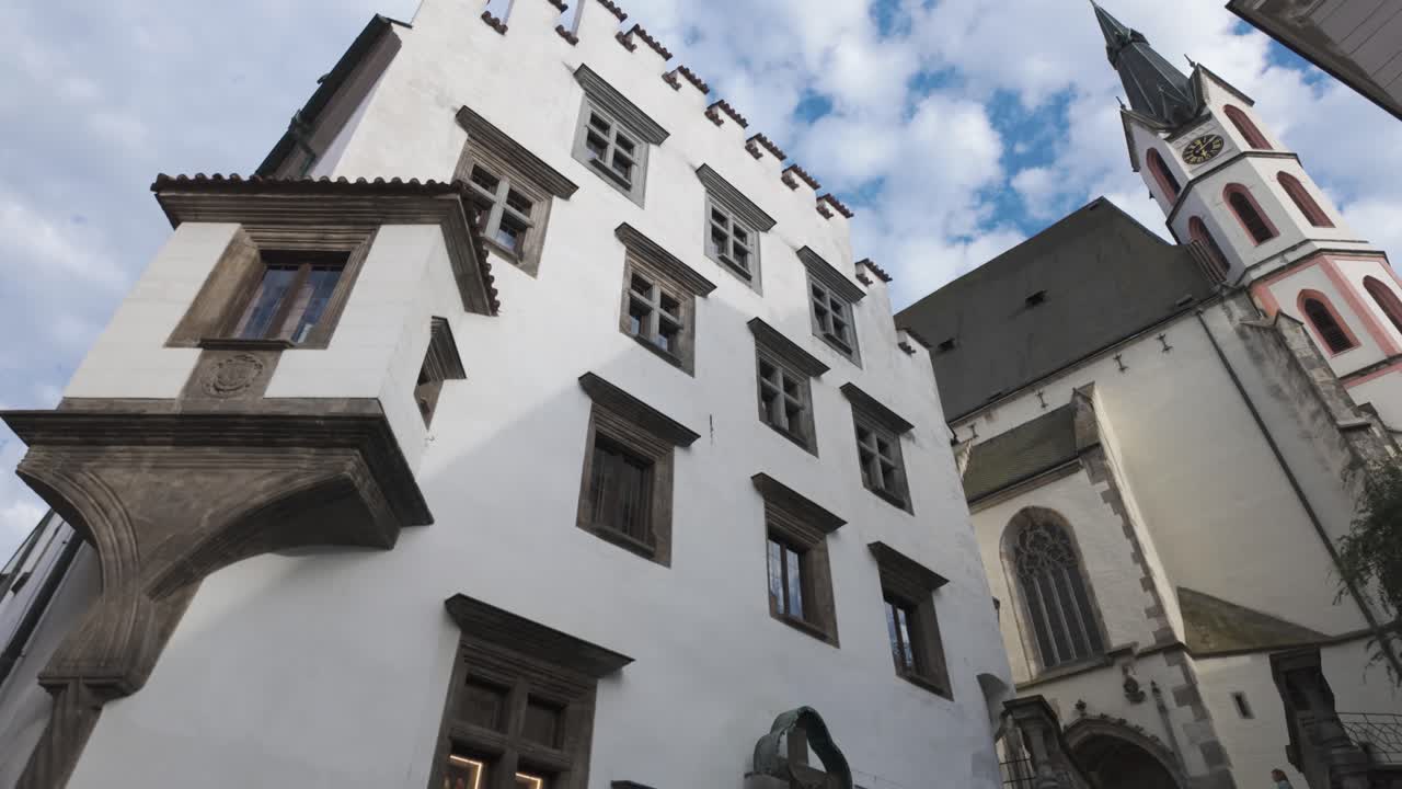 The historic Church of St. Vitus stands tall under a partly cloudy sky in Český Krumlov