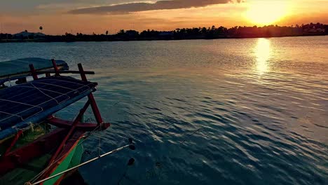 Silhouette-Eines-Festgemachten-Traditionellen-Khmer-Fischerbootes-Am-Flussufer-Von-Kampot,-Kambodscha