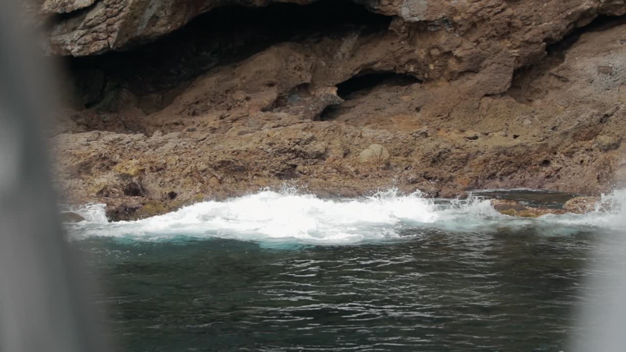 Ocean waves on rock formations. Filmed from vessel