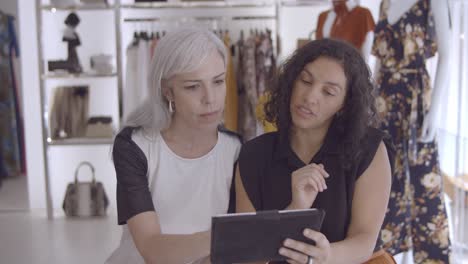 Focused-customer-and-shop-assistant-meeting-in-boutique-with-tablet-computer