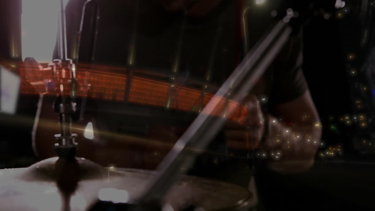 Male drummer playing behind cymbal stand in music studio, showcasing red LED streaks and LED panels