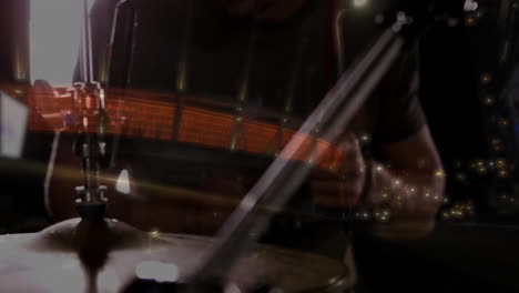 male drummer playing behind cymbal stand in music studio, showcasing red led streaks and led panels