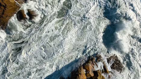 white foamy sea waves splashing against rocks in summer, carballo, a coruña, spain - aerial top
