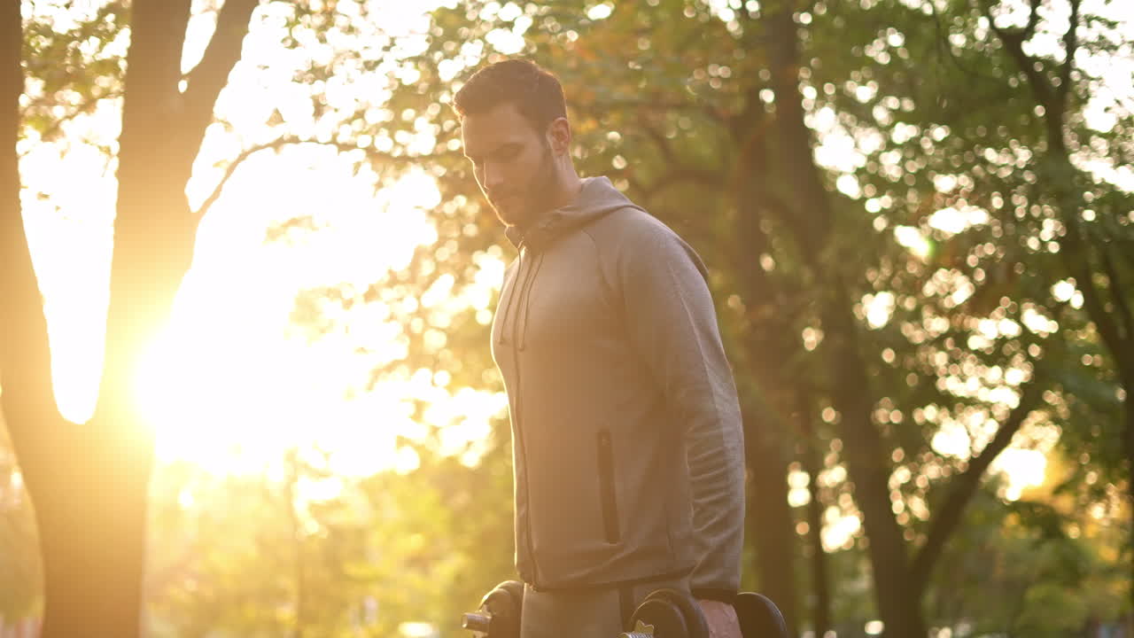 Man exercising with dumbbells outdoors in a park