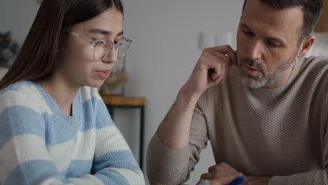 Kaukasischer-Mann-Hilft-Ihrer-Tochter-Im-Teenageralter-Bei-Den-Hausaufgaben-Zu-Hause