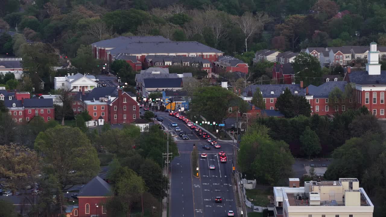 Aerial view of Main Street in Fairfax, Virginia,USA at dusk with cars in traffic, historic brick buildings and tree-lined streets illuminated by evening light in calm suburban city setting. Wide shot