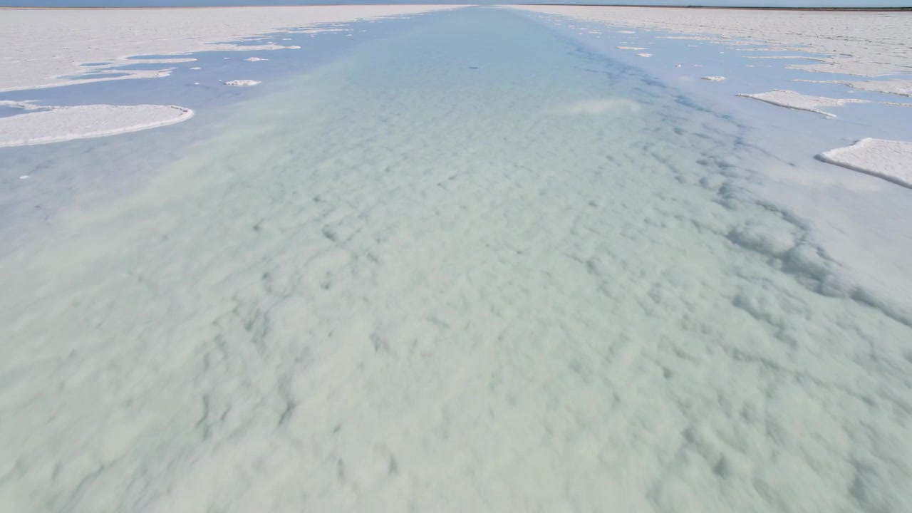 淡いティール色の水路が極地の海氷を切り裂き、融解した部分を明らかにする様子を調査する前進する航空カメラ。