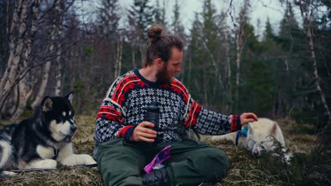 man sitting with his dogs in the woods - petting his dogs. - closeup shot