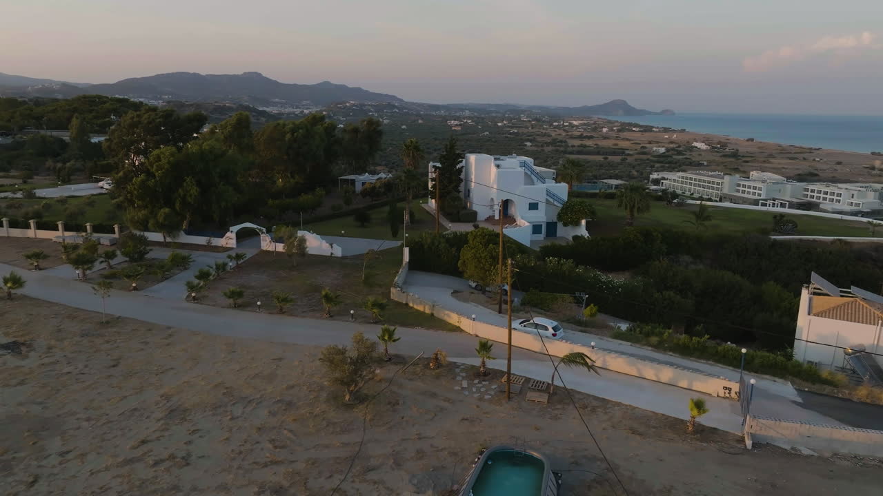 Panoramic drone shot of cars arriving at their villas, sunny evening in Greece
