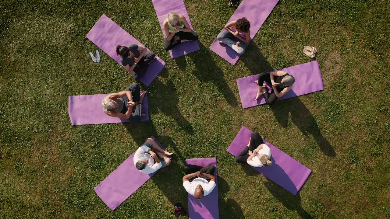 Drone Shot Of Teacher Leading Group Of Mature Men And Women In Class At Outdoor Yoga Retreat