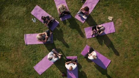 drone shot of teacher leading group of mature men and women in class at outdoor yoga retreat