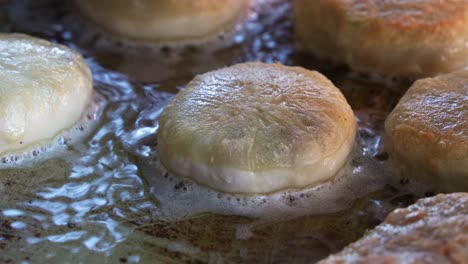 freshly made xian bing cooking in the pan, savoury minced pork pastry deep-fried until golden brown with a crispy outside, a popular handheld snack in taiwan, close up shot