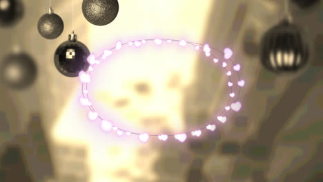 pink heart shaped fairy lights and hanging bauble decorations against aerial view of cityscape