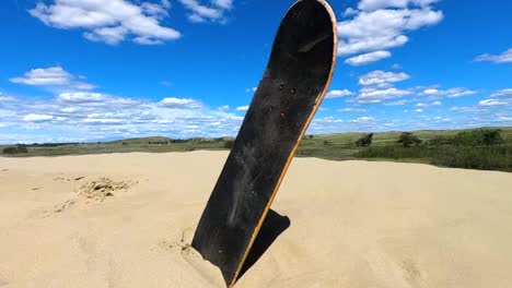 una tabla de skate sin ruedas que sobresale de la arena en un desierto en un día caluroso y soleado