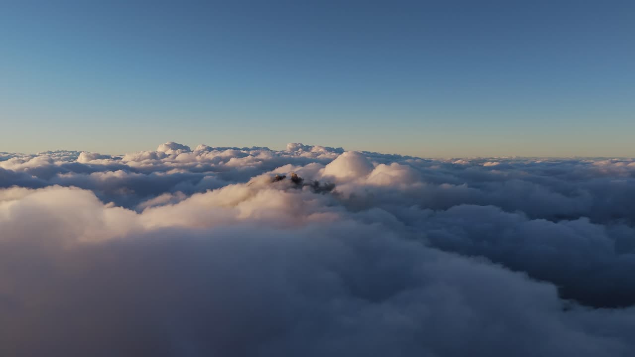 Volcan de Feugo hidden mostly by clouds, ash eruption above the clouds, drone shot at dusk