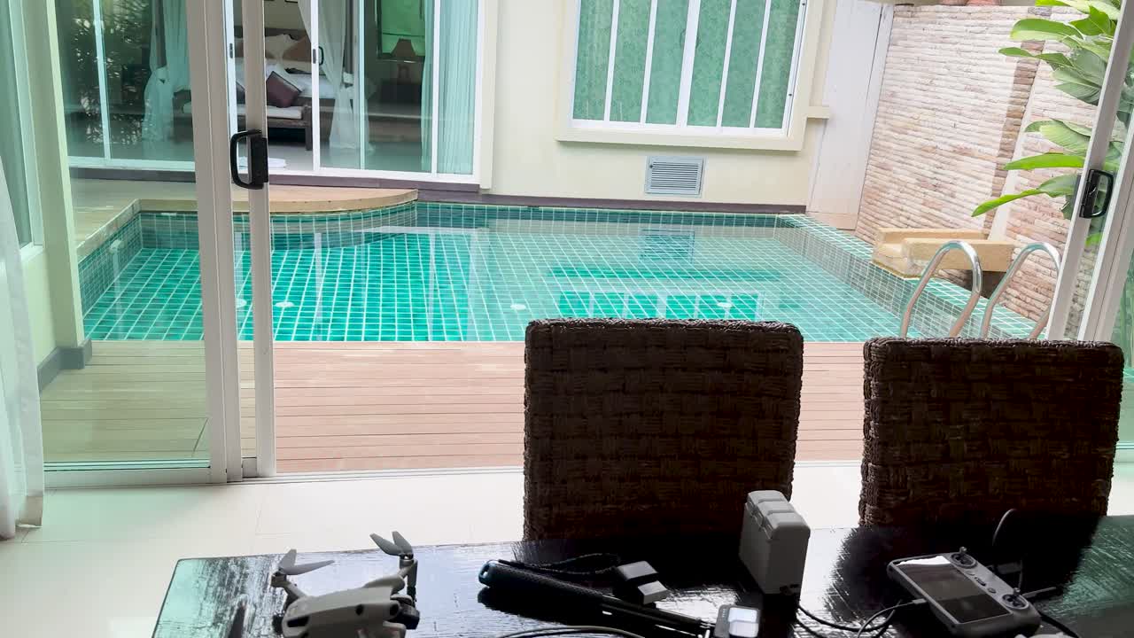 Camera pans from indoor dining area to outdoor pool, bright natural light, modern tropical home