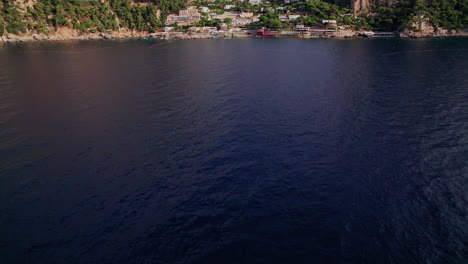 Una-Toma-Aérea-Que-Se-Eleva-Desde-El-Mar-Y-Se-Acerca-A-Las-Hermosas-Playas-De-Marina-Piccola-En-Capri,-Una-Famosa-Isla-Que-Es-Un-Popular-Destino-De-Vacaciones-De-Lujo-En-Italia-A-Lo-Largo-De-La-Costa-De-Amalfi