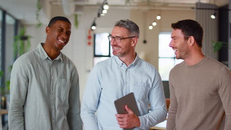 portrait of male multi-cultural business team with digital tablet in modern open plan office