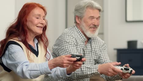 senior couple 50-60 years old playing football using video game at home sitting on the couch