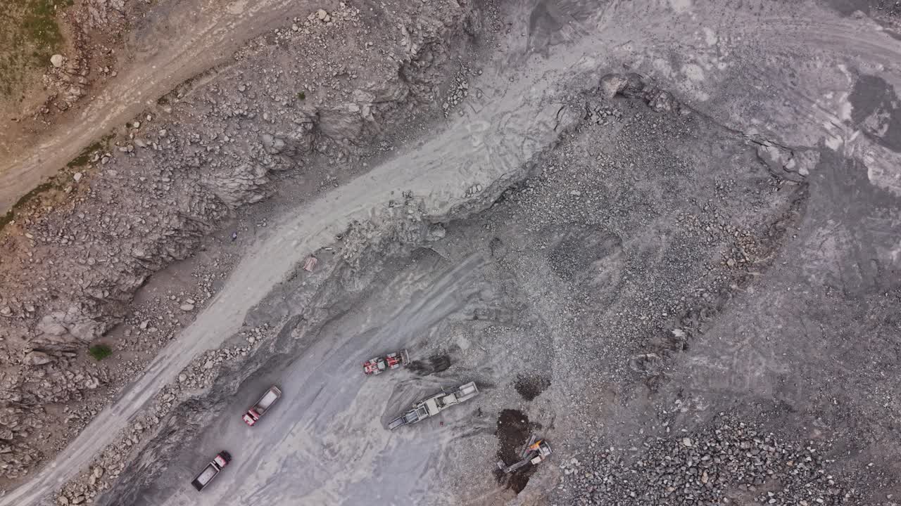 Vehicles move through a rocky industrial landscape by day