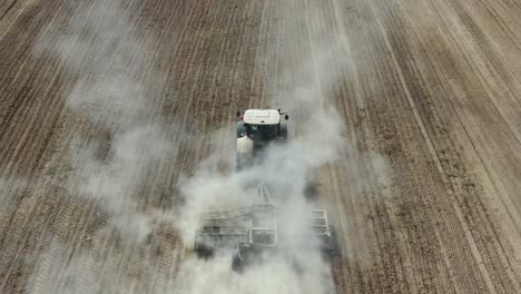 Puffy-Smoke-From-A-Tractor-With-A-Seeder-Sowing-In-A-Plowed-Field-In-Kyiv,-Ukraine---Drone-Shot,-Slow-Motion