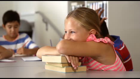 retrato de una niña bonita apoyándose en libros en la biblioteca