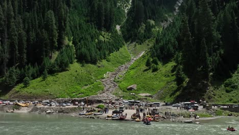 drone aerial footage of people at lake enjoying the rafting in valley with tall lush green trees