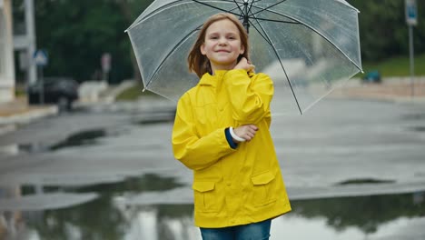 Portrait-of-a-happy-teenage-girl-in-a-yellow-jacket-with-an-umbrella-while-walking-in-the-park-after-the-rain