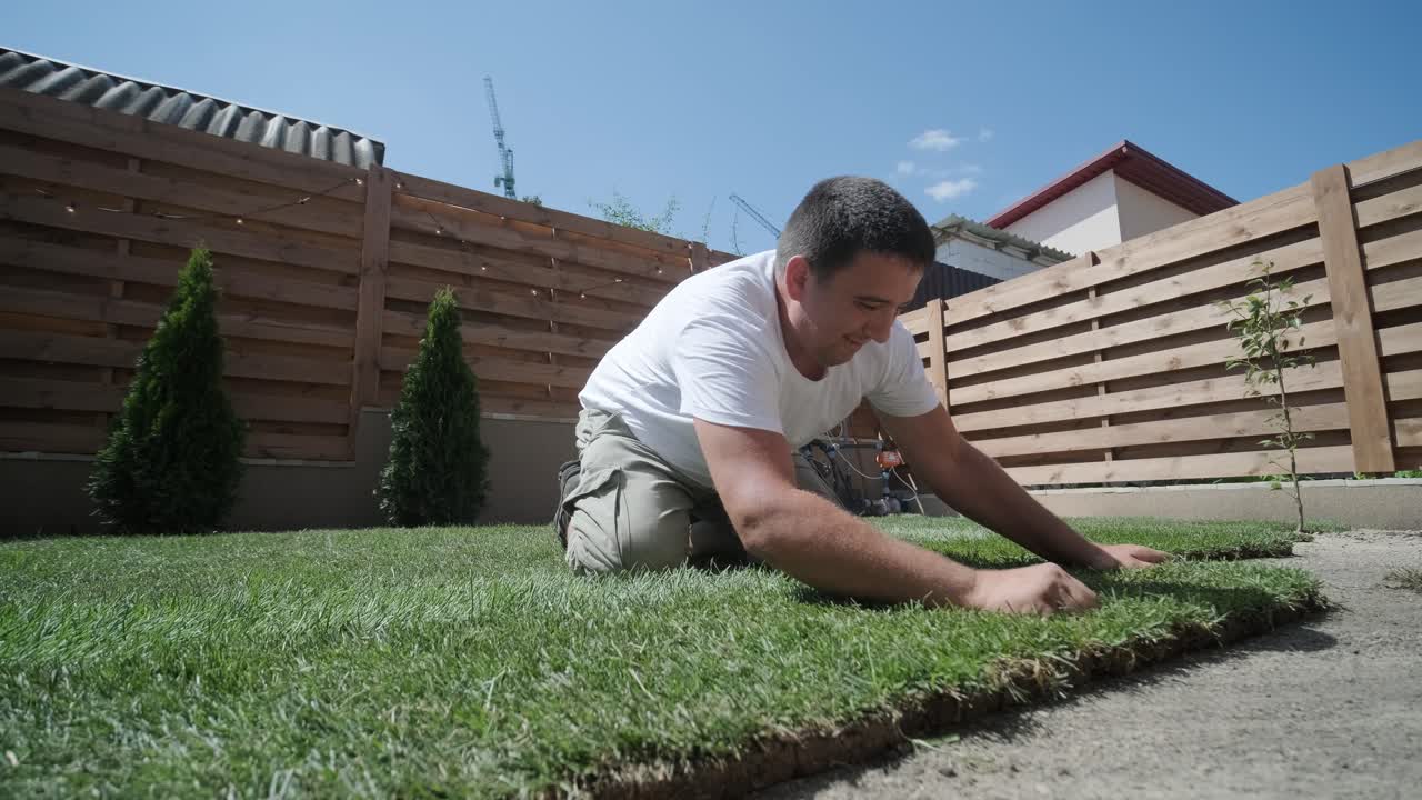 잔디 설치 및 조경 프로젝트를 위해 뒷마당 정원에 소드 풀을 는 사람, 주거 마당의 신선하고 푸른 잔디를 위해 집 개선 및 야외 유지에 초점을 맞추고 있습니다.