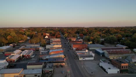 Aerial-view-over-a-downtown-waterfront-business-area-with-beautiful-and-colorful-autumn-trees-in-the-background-during-blue-hour