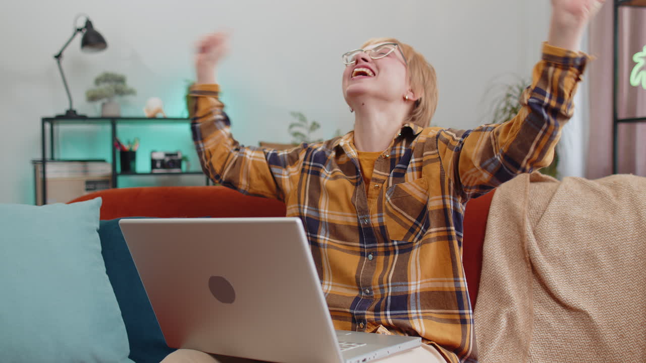 Erstaunliche junge Frau benutzt Laptop-Computer, erhält eine gute Nachricht, schockiert über den Sieg, feiert den Sieg.