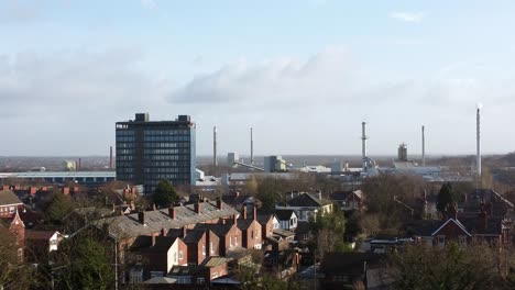 aerial view over park trees to industrial townscape neighbourhood with blue skyscraper, merseyside, england