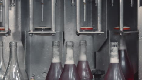 wide shot of a modern factory where glass bottles are automatically filled with wine on a production line.
