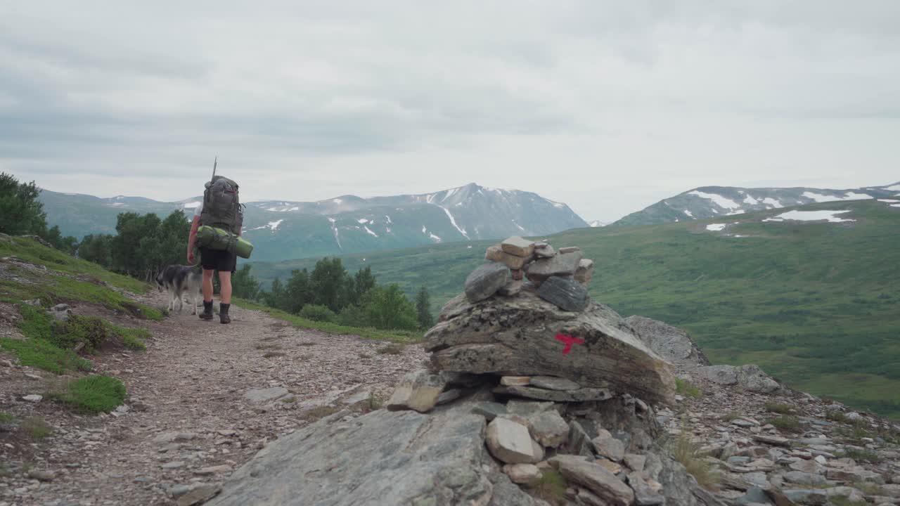 excursionista con un compañero de perro caminando en trekanten en la montaña trollheimen, noruega