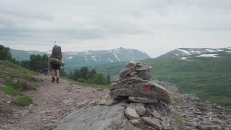 hiker with a dog companion trekking on trekanten in trollheimen mountain, norway