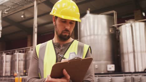 worker examining while writing on clipboard