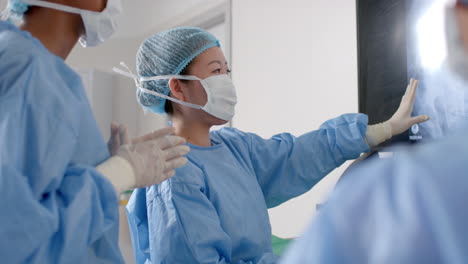 Diverse-female-surgeons-looking-at-x-ray-scans-in-operating-theatre,-slow-motion