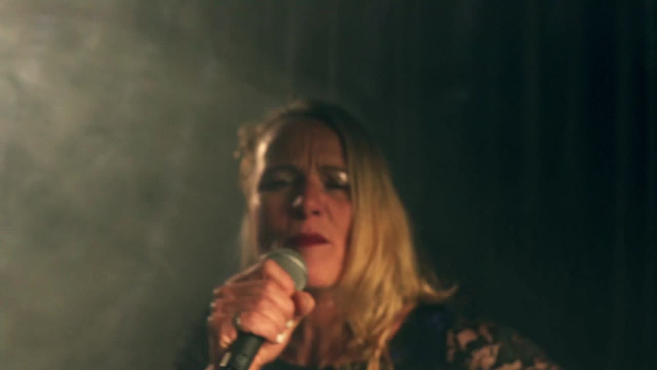 Medium shot of a talented singer playing a concert with her microphone on stage with strobe lights and a breathtaking performance