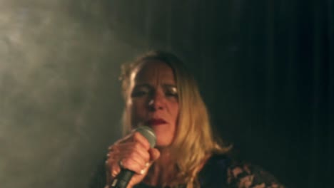 disparo medio de una cantante talentosa tocando un concierto con su micrófono en el escenario con luces estroboscópicas y una actuación impresionante
