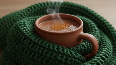 a cozy winter beverage: a warm mug of steaming cocoa wrapped in a soft green scarf, perfect for cold days and comforting moments
