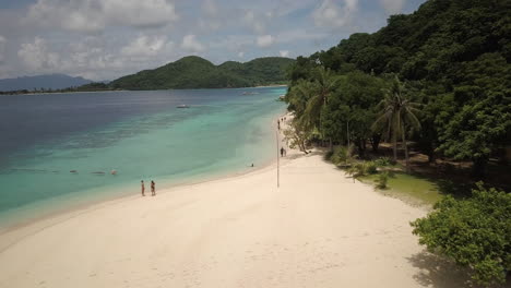 tropical island with white sandy beach and turquoise clear water in summer - aerial drone shot