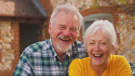 portrait of happy laughing retired senior couple outside dream home