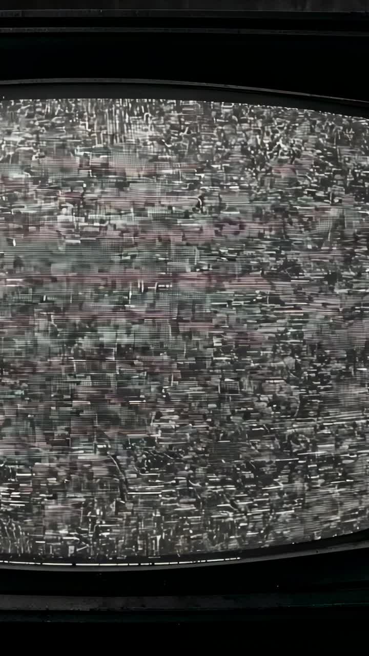 Vertical video: Flickering curved-oval CRT TV with static from signal noise in dark room, scanlines