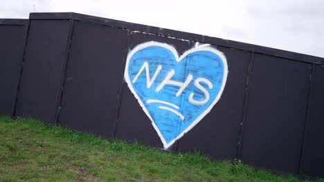 Street-art-and-graffiti-of-a-blue-heart-for-the-NHS-in-London-United-Kingdom,-support-to-the-national-health-service-during-Covid-19-Coronavirus-pandemic,-on-a-cloudy-day