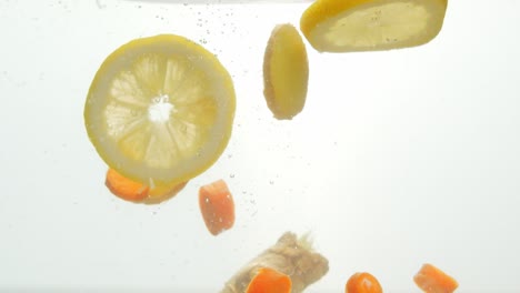 Freshly-chopped-lemon-and-carrot-dropped-into-water,-isolated-white-background