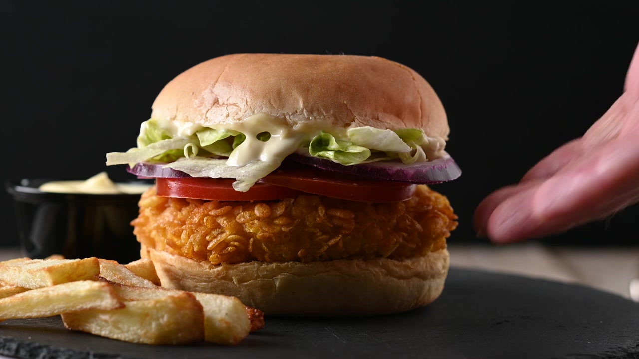 Mano che prende un hamburger di pollo croccante