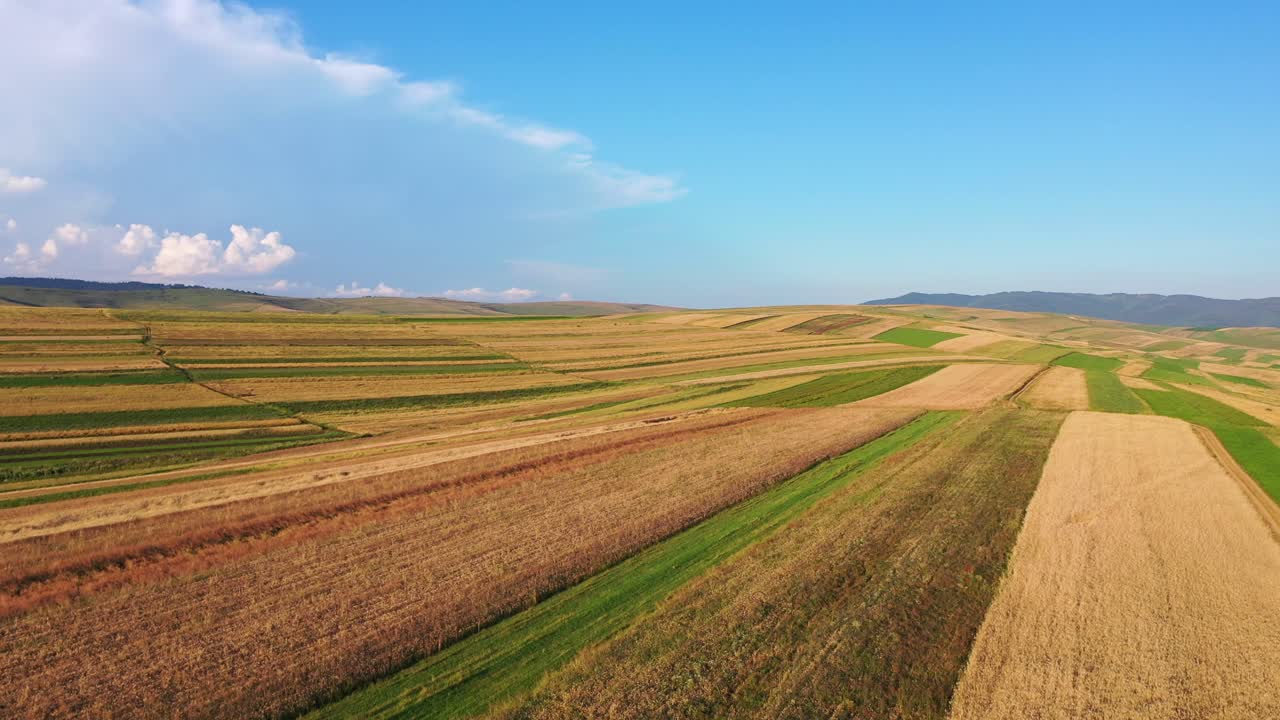 Drone footage of flying over vast farming fields of a hilly rural countryside